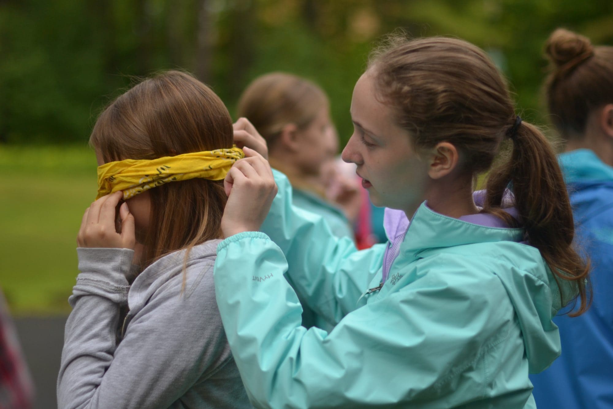 girl tying blindfold on her friend