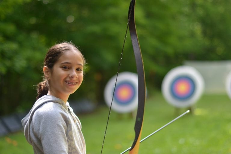 girl smiling at camera in front of archery targets