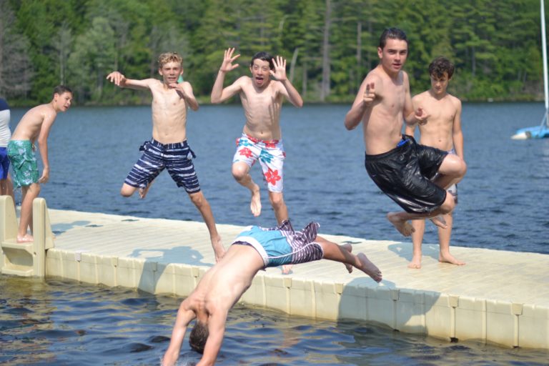 boys jumping off of dock into water
