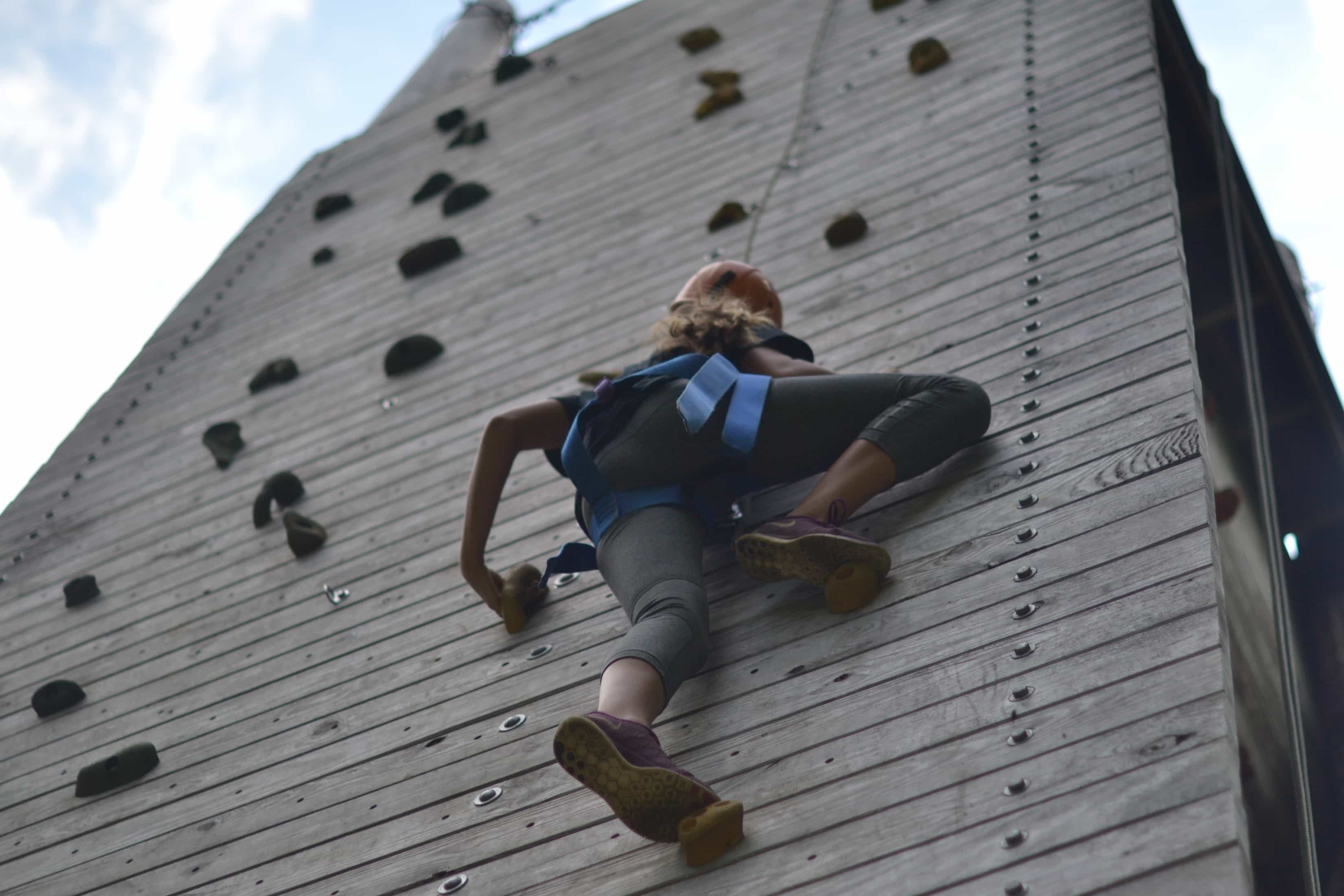 view from the ground of girl scaling the climbing wall