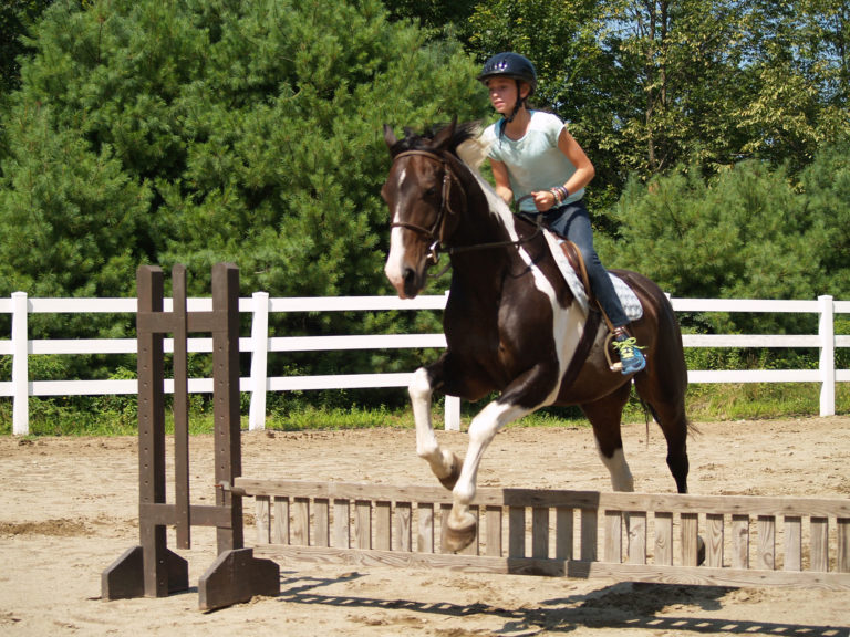 girl jumping horse at family camp